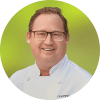 Jeff Miller, President of Morrison Healthcare, smiling in chef's coat against green background