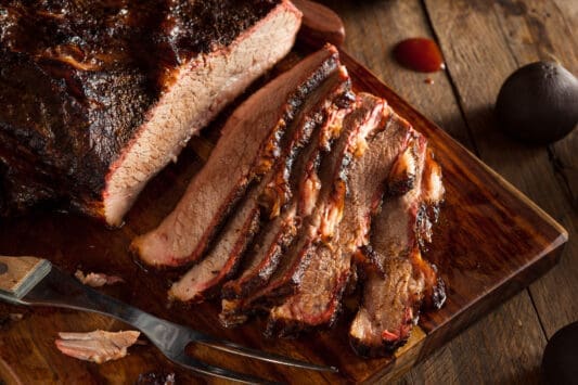 Sliced barbecue brisket on a wooden cutting board with a fork