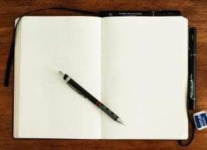 Open blank notebook with pen on wooden surface
