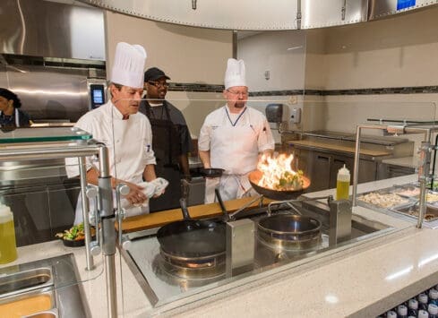 Chefs cooking over open flames in a modern commercial kitchen at Morrison Healthcare