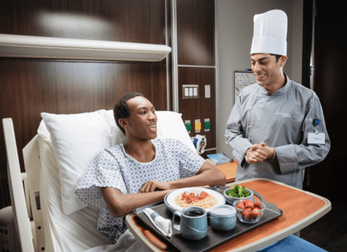 Man sitting in a hospital bed with a chef
