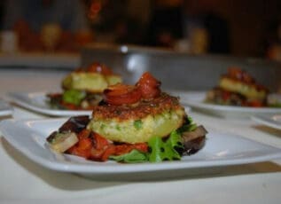 Grilled vegetable stack with tomato and herb crusted patty on salad