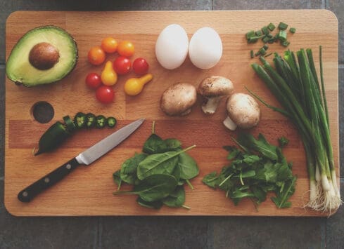 Fresh vegetables, eggs, and mushrooms on a cutting board, ingredients for a healthy meal