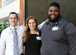 Morrison Healthcare associates smiling in hallway, wearing employee ID badges