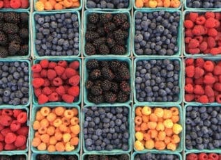 Colorful berries including blueberries, blackberries, raspberries and golden berries in cardboard containers