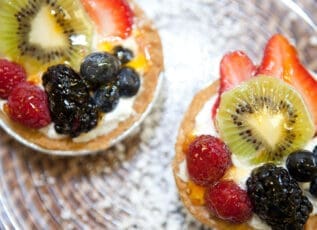 Fruit tart with cream, kiwi, berries and chia seeds on rustic wooden table