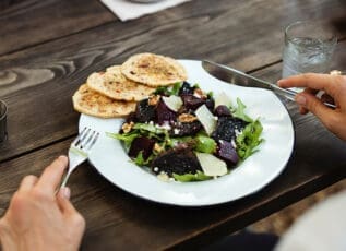 Beet salad with goat cheese and flatbread on rustic wooden table