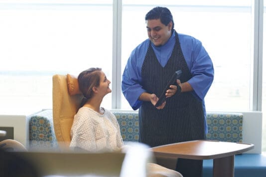 Chef smiling at young patient in hospital room