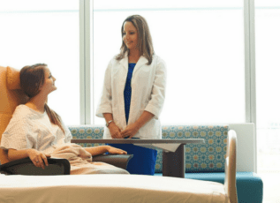 Two healthcare professionals consulting in patient room with modern decor and comfortable seating