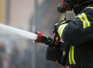 Firefighter spraying water from fire hose to extinguish fire