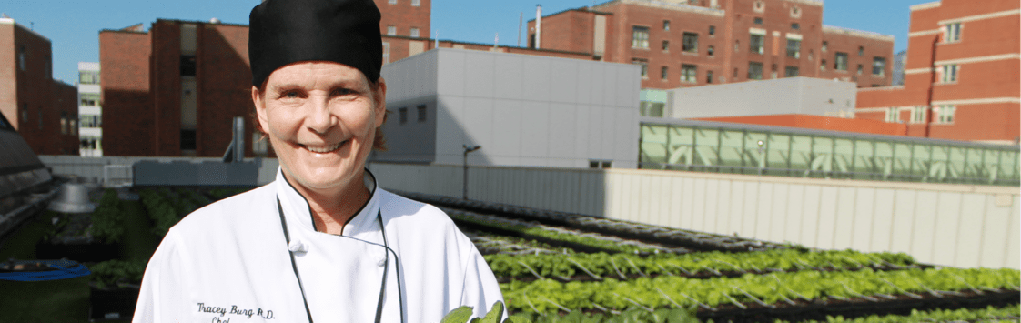 Chef smiling in front of vegetable garden on rooftop of urban building
