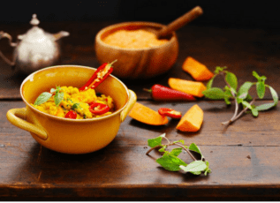 Creamy vegetable curry with peppers and herbs on rustic wooden table