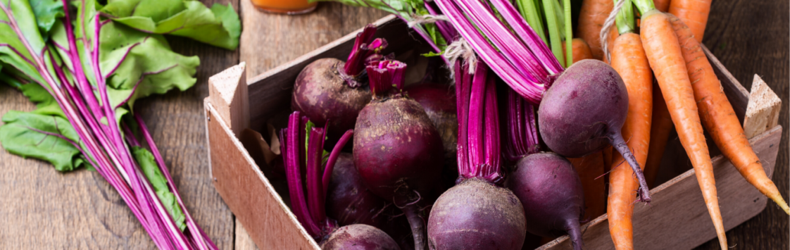Assorted beets and carrots in wooden crate on rustic table