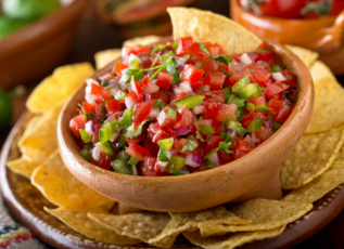 Fresh pico de gallo salsa with tomatoes, onions, and cilantro in a wooden bowl with tortilla chips