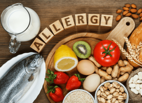Food allergy concept with dairy, wheat, eggs, fish, nuts and produce on wood background