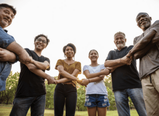 Group of diverse people standing together, holding hands in unity