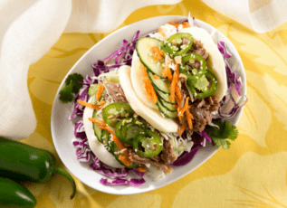 Braised pork tacos with cabbage slaw, cilantro, jalapeno, and cucumber on yellow napkin