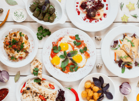 Nutritious breakfast dishes with vegetables, eggs, and spices on a white wooden table