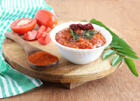 Tomato basil salsa with fresh tomato, basil leaves and spices served on a wooden cutting board