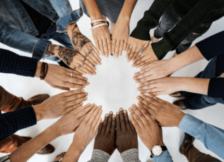 Group of diverse hands together in circle showing unity and teamwork