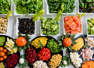 Colorful fresh vegetables, fruits and salad ingredients in bowls for healthy eating and nutrition