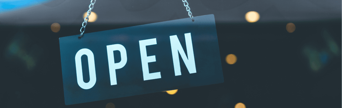 Blue hanging open sign with blurred lights in the background