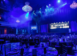 Elegant banquet hall set for Compass Stars on Broadway 2018 event with stage lighting and chandeliers