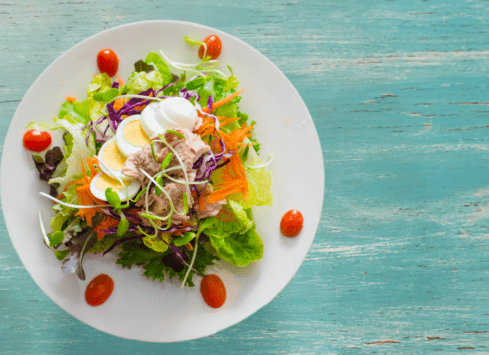 Fresh garden salad with mixed greens, tomatoes, eggs, and carrots on a white plate