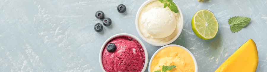 Colorful fruit sorbets with blueberries, lime, and mint leaves on a light background