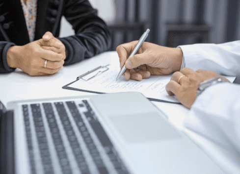 Business meeting signing contract, hands with pens over document on desk with computer keyboard