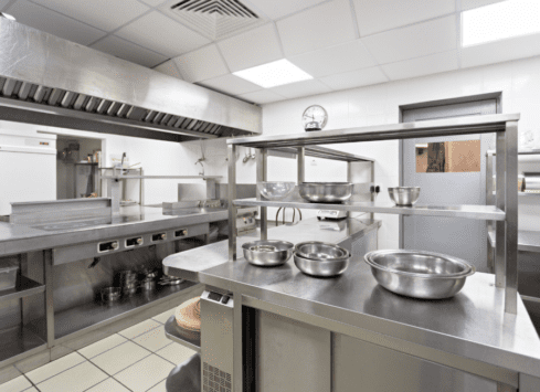 Commercial kitchen with stainless steel counters, appliances, and ventilation hood