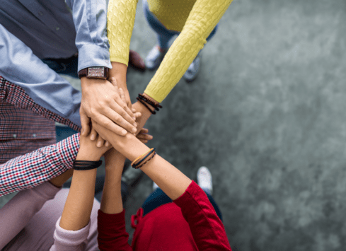 Group of diverse hands stacked together in unity