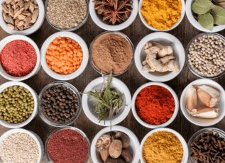 Colorful spices and herbs in bowls on a wooden table for cooking flavorful, healthy meals.