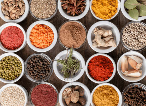 Colorful spices and herbs in bowls on a wooden table for cooking flavorful, healthy meals.