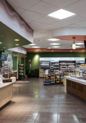 Modern cafeteria interior with fresh food displays, beverage station, and seating area