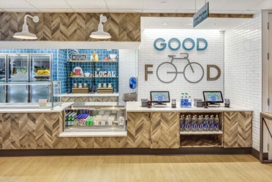 Morrison Healthcare Good Food cafe with herringbone backsplash, grab-and-go items, and bicycle decor