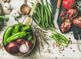 Fresh vegetables, fruits, grains, and cotton flowers on a rustic wooden table