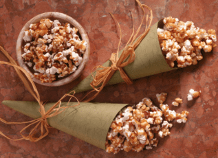 Caramel popcorn cones wrapped in raffia on rustic background