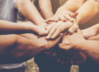 Group of diverse hands joined together in unity and teamwork