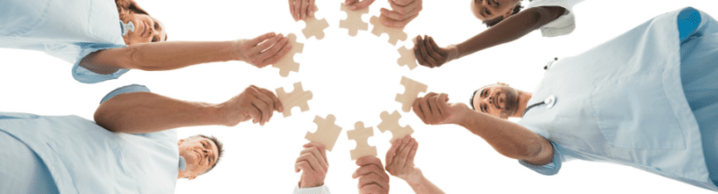Doctors and nurses join hands forming puzzle piece symbolizing teamwork in healthcare