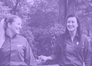 Two smiling female Morrison Healthcare employees outdoors in professional uniforms