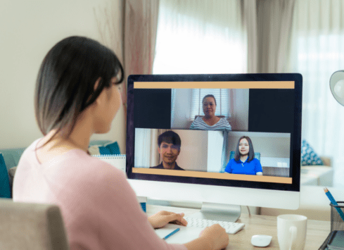 Woman on video call with three colleagues displayed on desktop computer screen