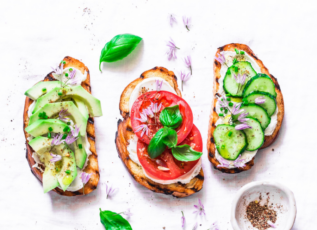 Avocado toast with tomato, cucumber, and herbs on white background