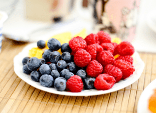 Berries on white plate: fresh blueberries and raspberries for healthy snack or dessert