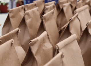Rows of brown paper lunch bags folded at the top, ready for meal distribution
