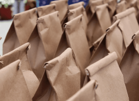 Rows of brown paper lunch bags folded at the top, ready for meal distribution