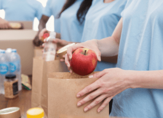 Volunteers packing healthy meals with fresh apples at food bank