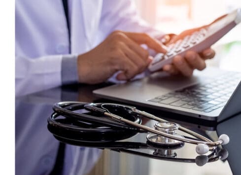 Doctor using laptop with stethoscope, providing healthcare technology solutions