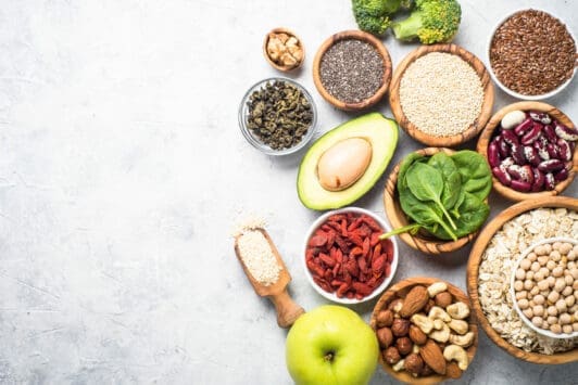 Healthy superfood ingredients: nuts, seeds, beans, grains, fruits and vegetables on gray background