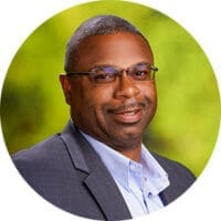 Smiling African American businessman wearing glasses and gray suit jacket, green background